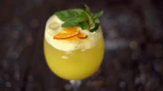 A glass of yellow lemonade with mint on a wooden surface