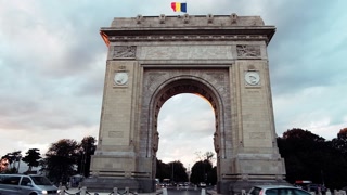 Bucharest, Romania - April 24, 2021: Cars moving near The Triumphal Arch at sunset