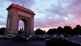 Bucharest, Romania - April 24, 2021: Cars moving near The Triumphal Arch at sunset. Vertical