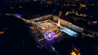 View of the Historic Centre of Sibiu with Christmas fair, Romania. The Great Square decorated with ferris wheel, Christmas tree, ice rink, illumination, old buildings and multiple people