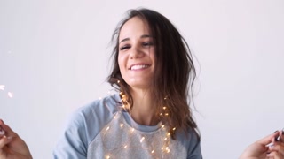 Festive mood with sparklers. Person in pajamas with sparklers and a garland waiting for the holidays on a white background