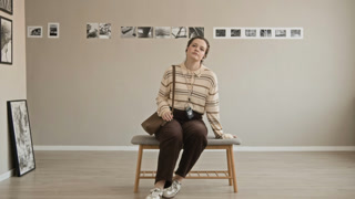 Full POV shot of young Caucasian girl following audio tour in modern art gallery and taking seat to observe exhibition while looking at camera