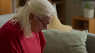 Caucasian senior woman reviewing past due bills, typing on laptop, and using calculator at home. Footage is perfect for commercial use in senior financial planning or retirement services ads