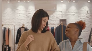 Two friends shopping for clothes together in a modern store