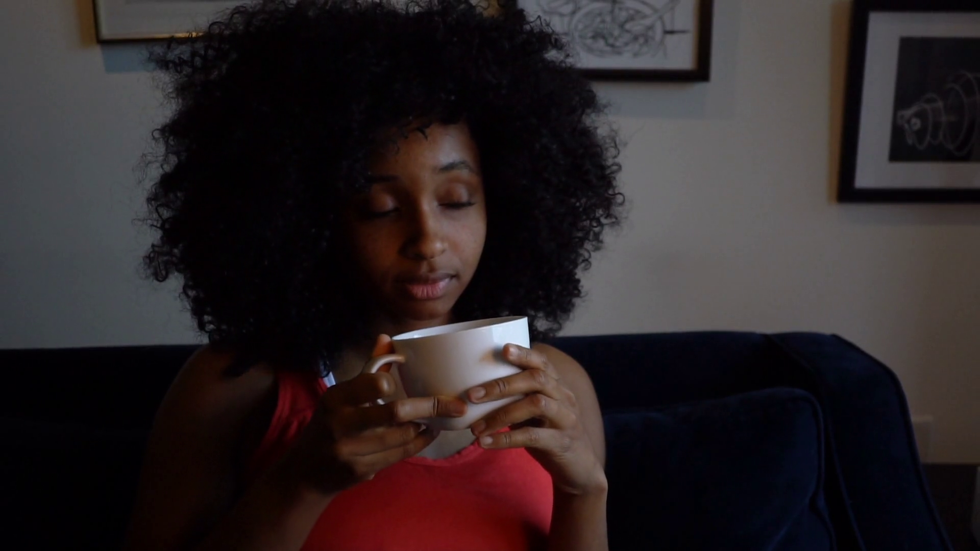 Young African American woman drinking coffee or tea at ...