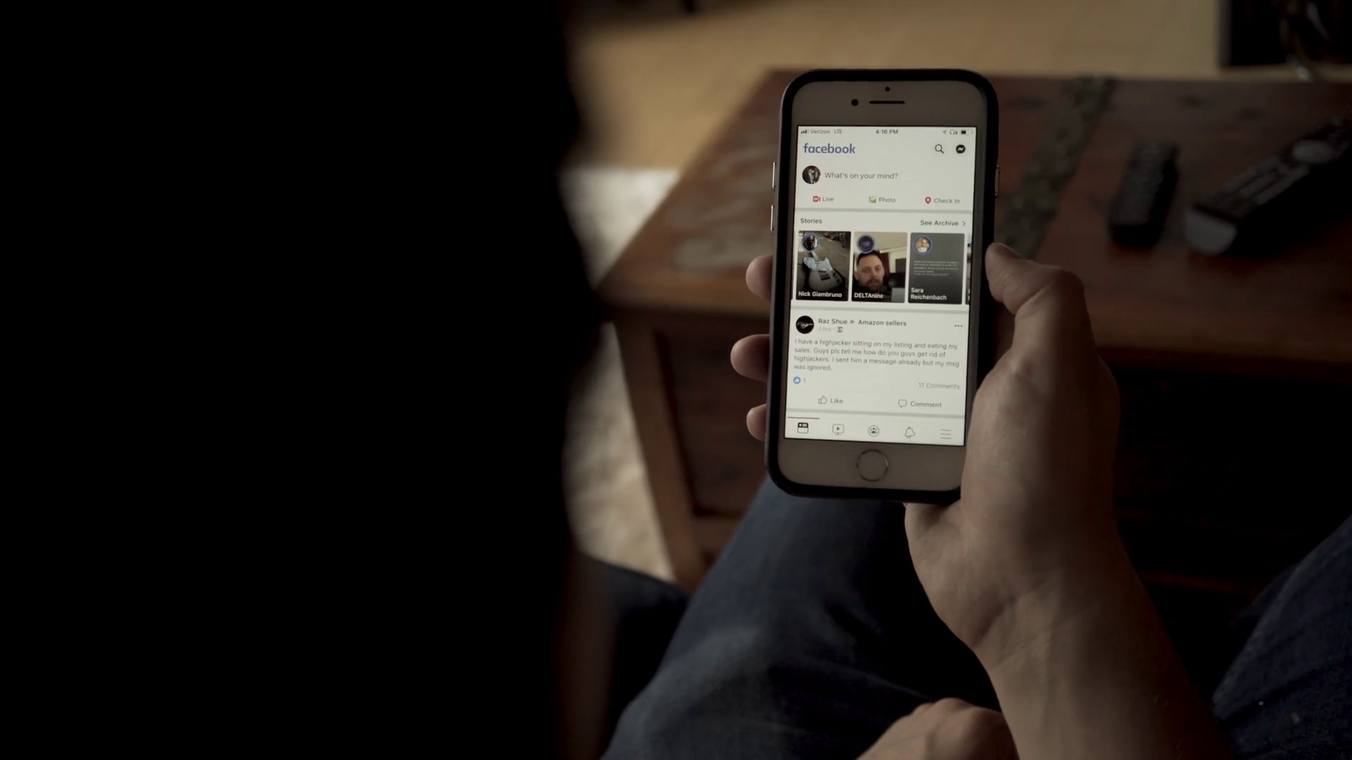 Young Man Scrolling iPhone with Facebook social media app open Stock