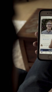 Young Man Scrolling iPhone with Facebook social media app open
