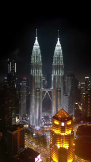 Aerial view of the illuminated Petronas Towers piercing the dark skyline, a glowing beacon amidst the city lights, Kuala Lumpur, Federal Territory of Kuala Lumpur, Malaysia.