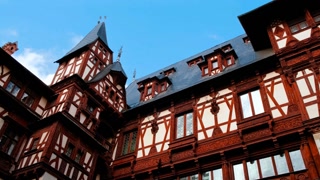 SINAIA, Romania, 12 October 2024 - Peles Castle, Sinaia, Transylvania, Romania, rises with turrets and timber framing, set against forested slopes, presenting a picturesque royal residence