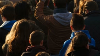 Closeup of an anonymous cross-generation crowd attending a memorial event