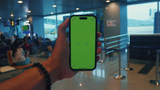 Close up phone with green screen in airport lounge. Mobile advertising concept for brands. Mobile advertising suits app promo, fintech ads
