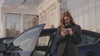 Portrait of a business woman. A woman stands next to the car and solves problems related to business. Woman making notes on her