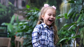 The young child joyfully celebrates, a butterfly perched on her head.
