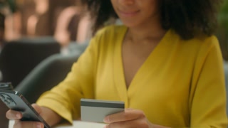 Close up young African American woman holding smartphone mobile phone bank card payment shopping buy happy female satisfied cash credit