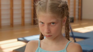 Angry girl looking at camera close up sad frustrated offended child kid pupil student annoyed schoolgirl in gym upset irritated grumpy