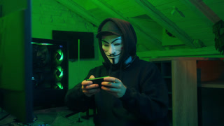 Lviv, Ukraine - June 03, 2024: Man in mask using mobile phone smartphone anonymous looking at camera technology program secure stealing