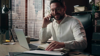 Smiling Caucasian man glad executive male guy agent talk mobile phone negotiation with client business in office worker salesman typing