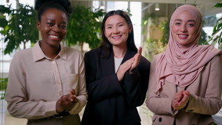 Smiling diverse businesswomen African Muslim Asian multiracial happy satisfied girls business partners three women in office congratulation