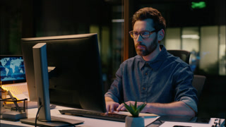Businessman employee in dark night office wearing eyeglasses business man working computer online trading late overtime male guy