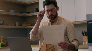 Caucasian man male renter reading paper bill pay online homeowner guy managing bank finances with papers check taxes documents rental rates