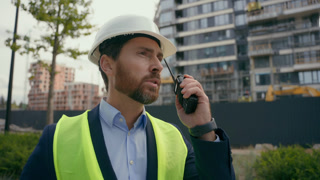Caucasian builder architect engineer contractor repairman outdoors in city talk with remote radio building urban development industry man
