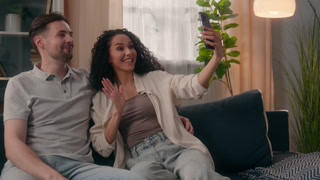 Happy family multiracial couple smiling talking video call smartphone Caucasian man guy male Hispanic Latino woman girl female at home talk