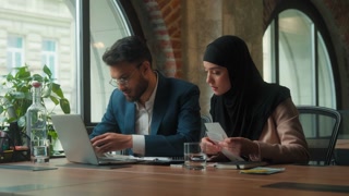 Arabian business team concentrated paperwork stress together in office Muslim Hindu two colleagues focused managing bills pay taxes with