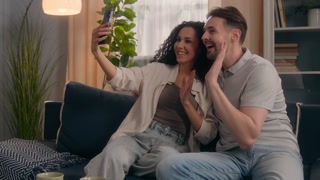 Happy family multiethnic couple smiling talking video call smartphone waving hand at home Caucasian man guy male Hispanic Latino woman girl