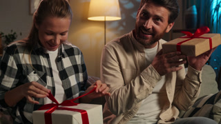 Caucasian middle-aged family exchange gift boxes anniversary celebration happy spouses adults man with woman giving presents surprise