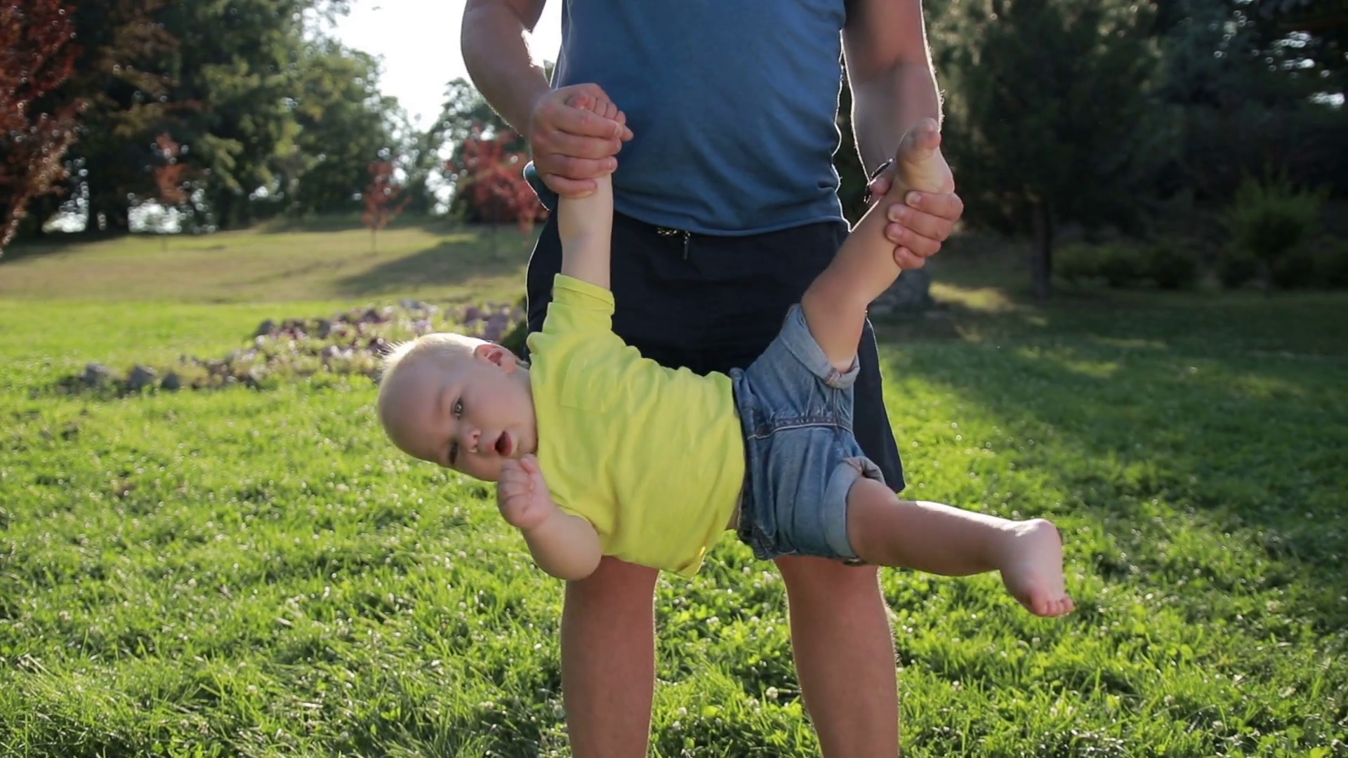 Father swinging toddler son upside down in park Stock Video Footage