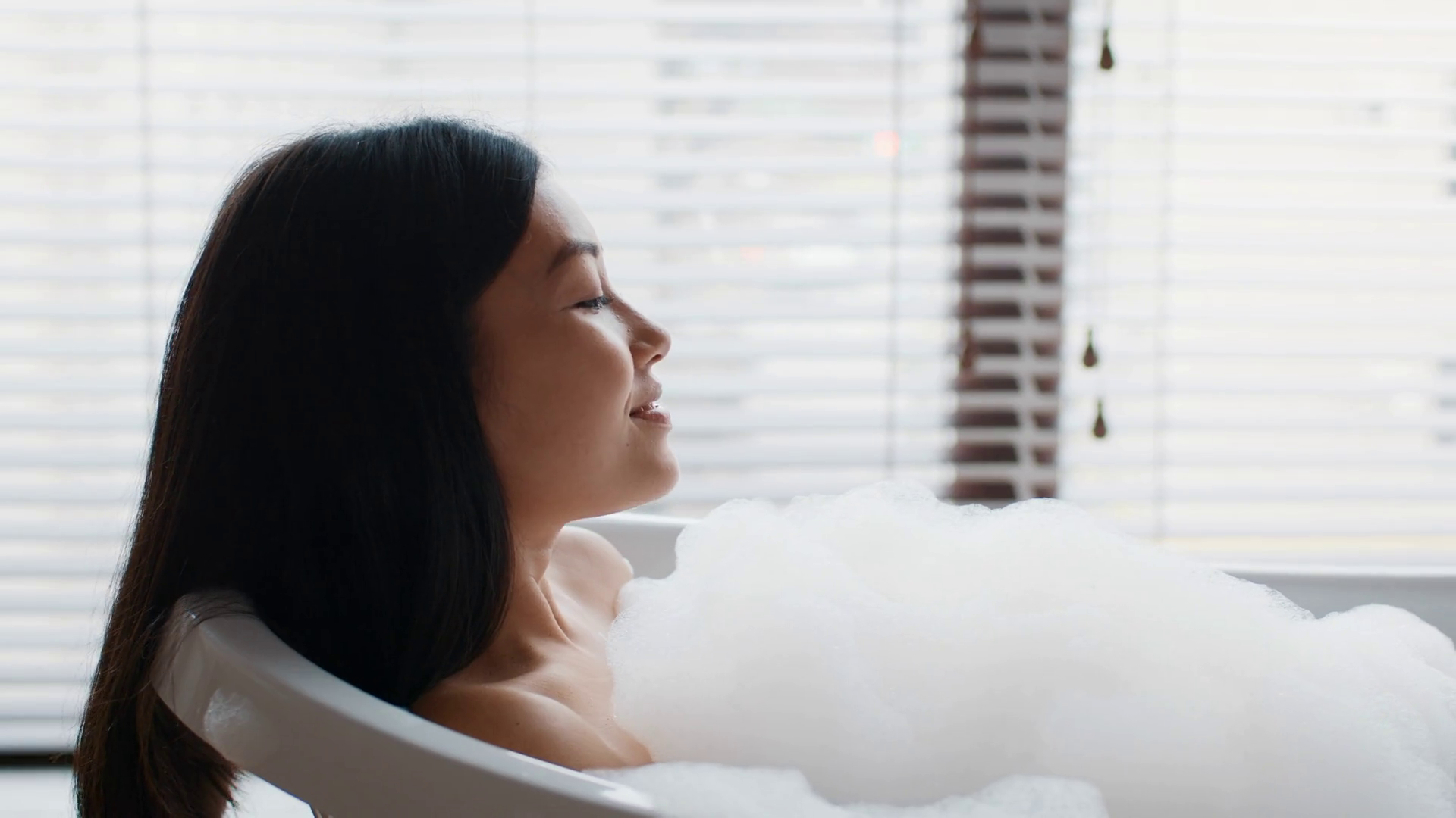 Japanese Lady Bathing With Foam Lying In Bathtub In Bathroom Stock