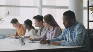 Study time. Group of multiethnic college students sitting on lesson and taking notes, listening to teacher in classroom