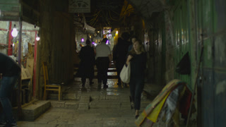 People walking on a cobblestone street at night