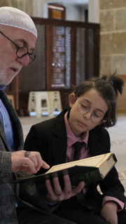 Little boy and his grandfather learning the Quran in the mosque, family studying the Quran on a