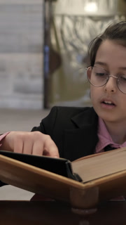 Little boy with reading Qur'an on wooden, boy reading Quran inside mosque made of stone, child