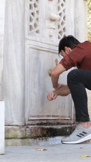Back view of Muslim bearded man performing ablution, a man washing his arms and elbows at mosque