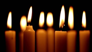 Many candles are burning and giving light around, light of candles burning in a dark place with no light illuminates environment with a soft light, selective focus