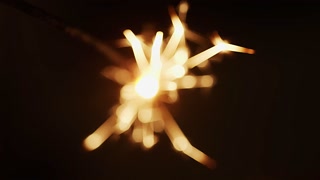 Blurred view of yellow sparks from a sparkler on a black background close-up. Fun and holiday concept