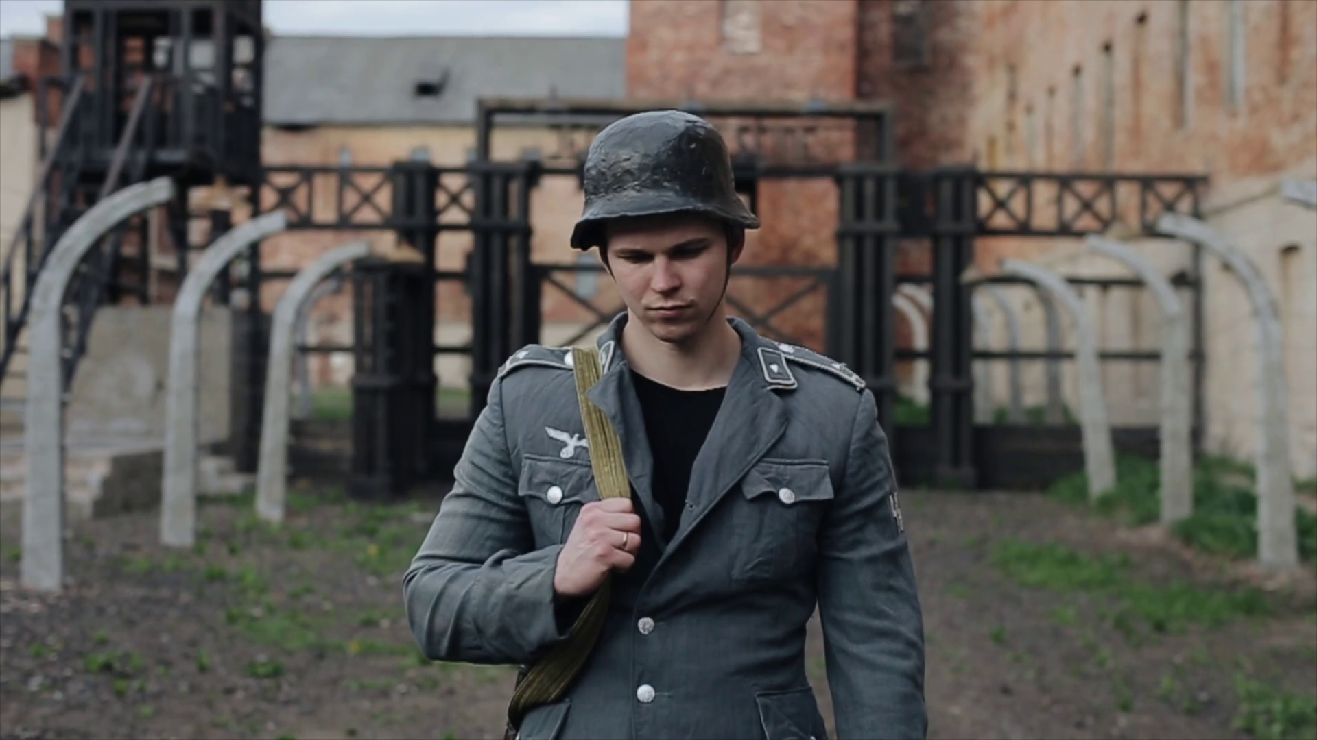 Portrait of a sad German soldier standing in front of a concentration