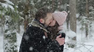 Fashionable millennials enjoying a snowy forest together. Candid footage of a young couple. Slow motion.