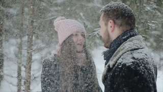Fashionable millennials enjoying a snowy forest together. Candid footage of a young couple. Slow motion.