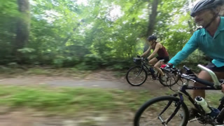 Mature man and woman bike down a dirt path by the C and O Canal in Maryland, enjoying the outdoors near the Potomac River