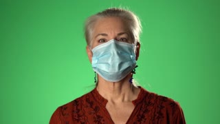 Woman takes off medical mask. Female breathes deeply and smiling looking at camera. Isolated on green screen background. Health care and medical concept. Close up portrait. 4k