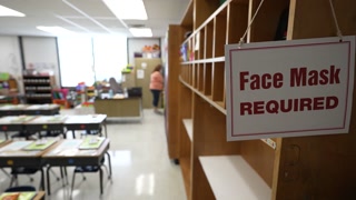 Face Mask Required sign in empty school classroom during pandemic.