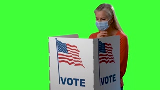 Conceptual green screen of mature woman medical face mask in voting booth at ballot box, careful decision for presidency, congress, senate in US election during pandemic.
