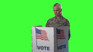Conceptual green screen portrait of smiling woman military service Army member in voting booth at ballot box, careful decision for president in US election.