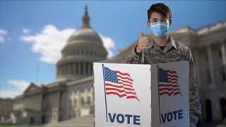 Conceptual portrait US Capitol background with smiling teen man wearing face mask giving thumbs up, in voting booth at ballot box, careful decision for president in US election.