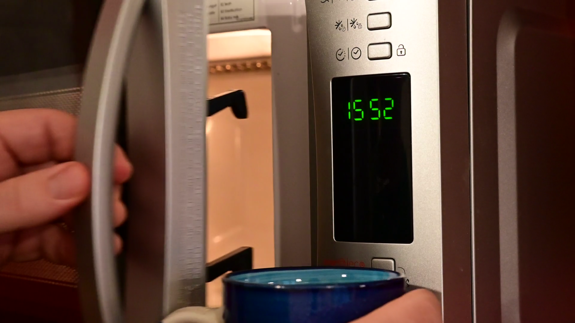 Closeup shot of the microwave oven timer. The oven is opened, the cup