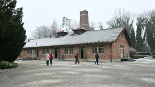 DDachau, germany, december 27, 2025. Visitors walking in front of the crematorium building at the concentration camp memorial site on a cold, snowy winter day.