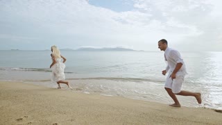 Couple jogging on sandy beach - slow motion.